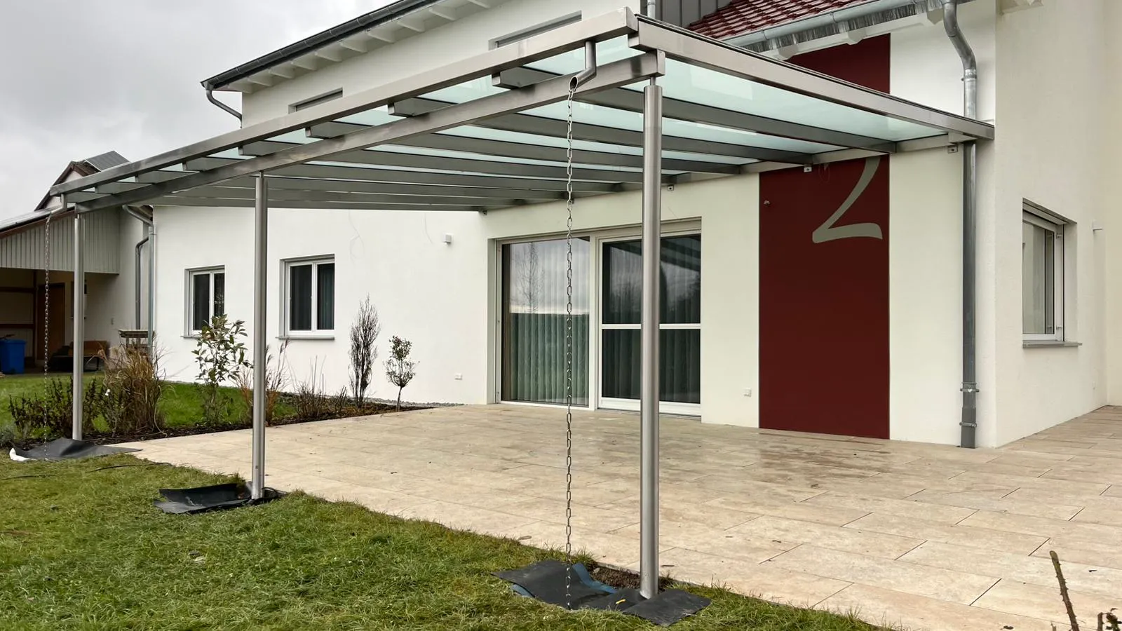 Terrassenüberdachung aus Edelstahl mit Glasdach an einem Einfamilienhaus