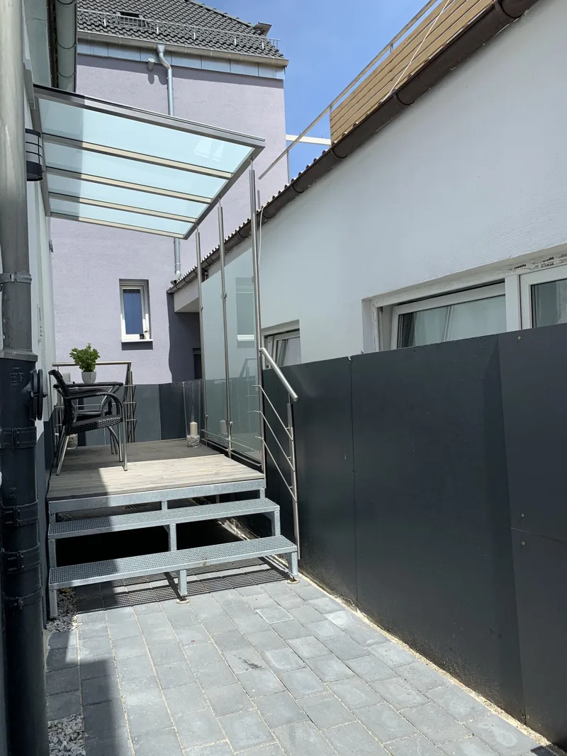 Balkonpodest mit Glas-Vordach und verzinkter Stahltreppe im Innenhof