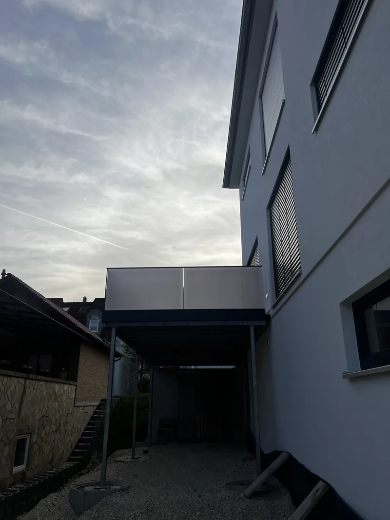 Anbaubalkon mit heller Plattenfüllung über der Einfahrt