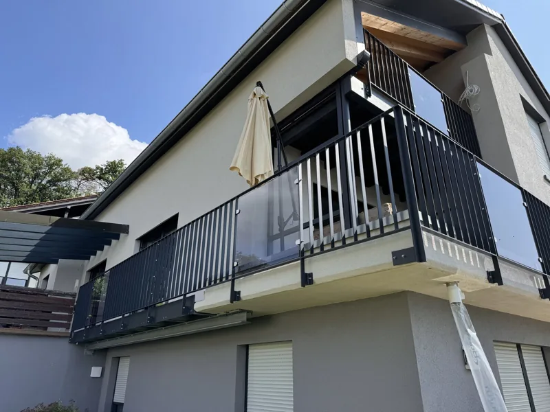 Anbaubalkon mit Glasgeländer und Sonnenschirm an einem Einfamilienhaus