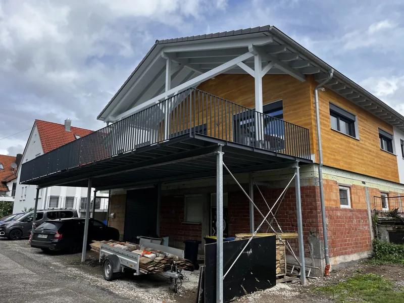 Vorstellbalkon über dem Stellplatz an einem Haus mit Holzfassade