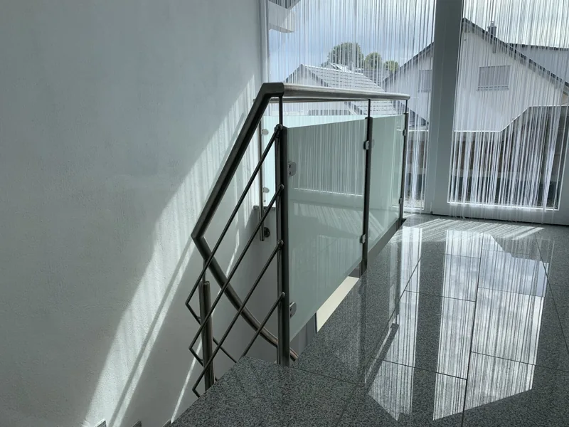 Edelstahlgeländer mit satiniertem Glas am Treppenabgang einer Galerie