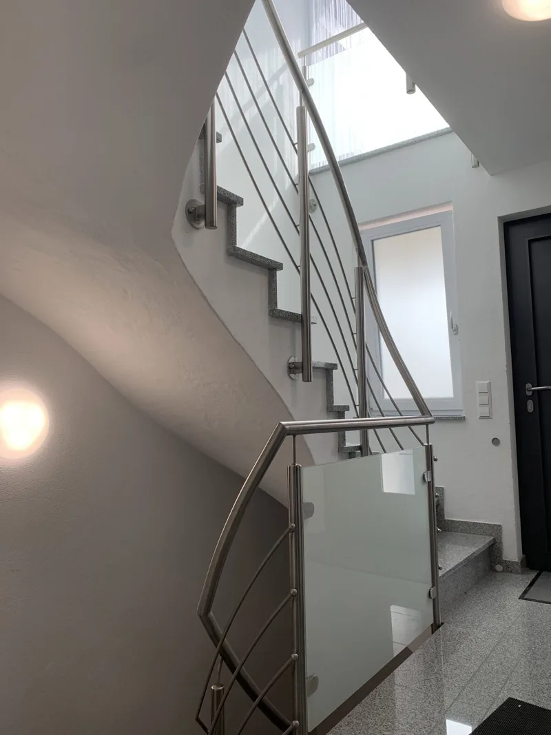 Edelstahlgeländer mit Glasfüllung an einer gewendelten Innentreppe