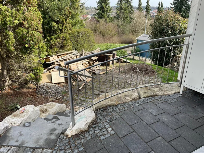 Geschwungenes Stahlgeländer am Treppenabgang im Garten