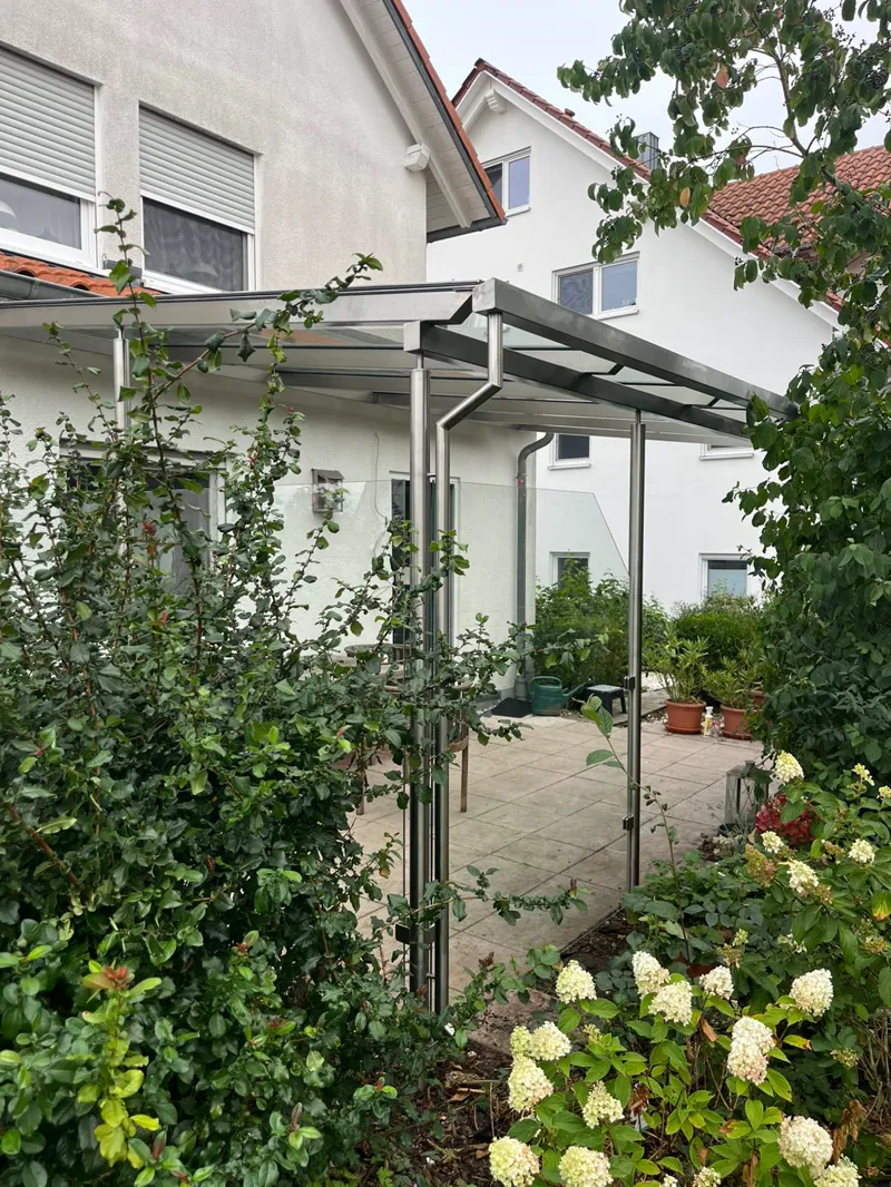 Edelstahl-Überdachung mit Glaswand im Garten